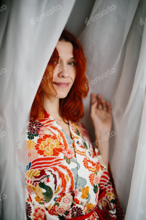 Preview: Woman peeking from behind white curtain smiling