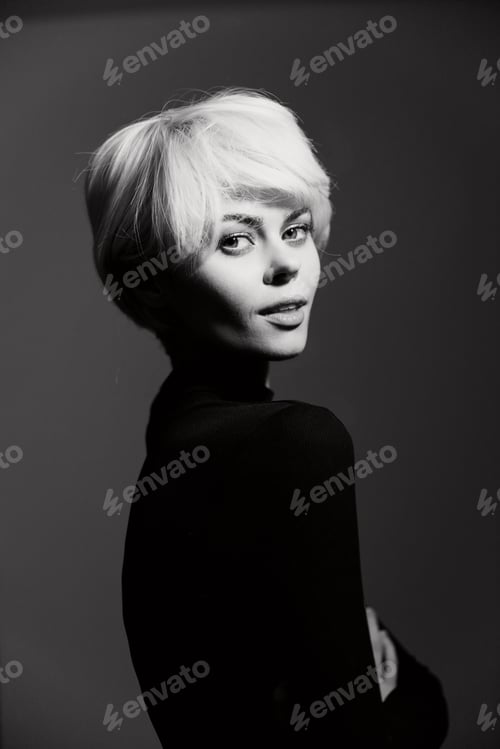 Preview: Elegant young woman with short blonde hair posing confidently against a dark background. Captivating