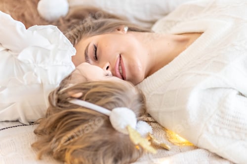 Preview: Mom and baby are lying on the bed at home and hugging. The happiness of motherhood, tender family