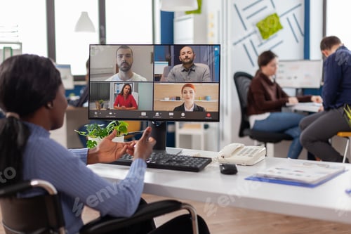 Preview: Paralyzed black worker sitting immobilized in wheelchair having videomeeting