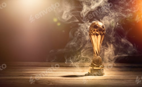 Preview: Gold football or soccer sports trophy cup on wood desk with dramatic strong contrast light