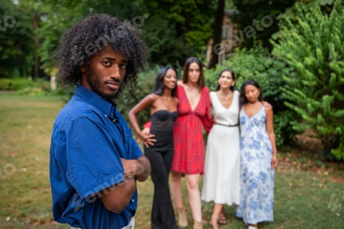 Preview: Portrait of an African boy with 4 girls looking at him in the background, multi ethnic group