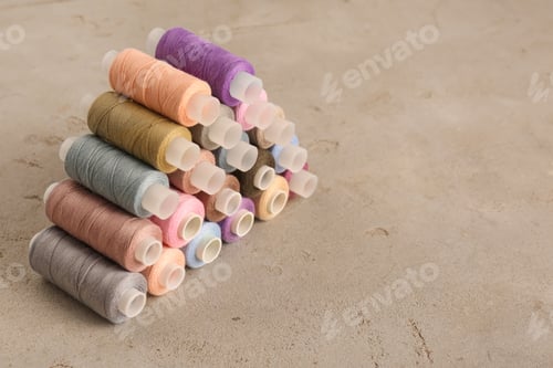 Preview: Set of color sewing threads on grey table, space for text