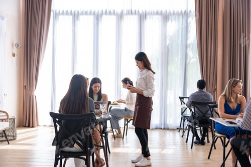 Preview: Asian waitress serving food to female customer in restaurant cafe.