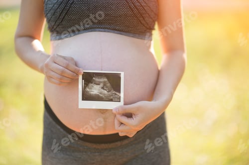 Preview: Pregnant woman holding ultrasound image of her child