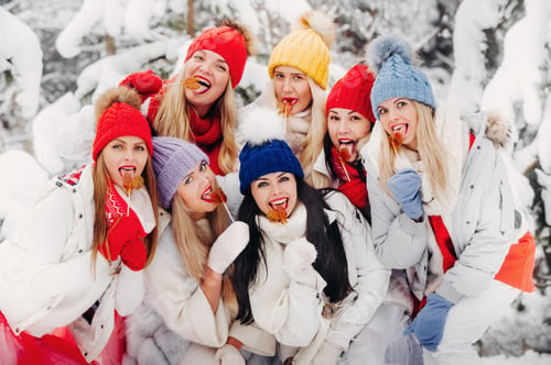 Preview: A large group of girls with lollipops in their hands stands in the winter forest.Girls in red and