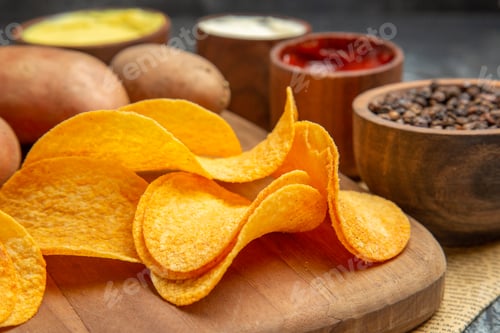 Preview: High resolution view of homemade delicious potato chips on wooden cutting board different spices and