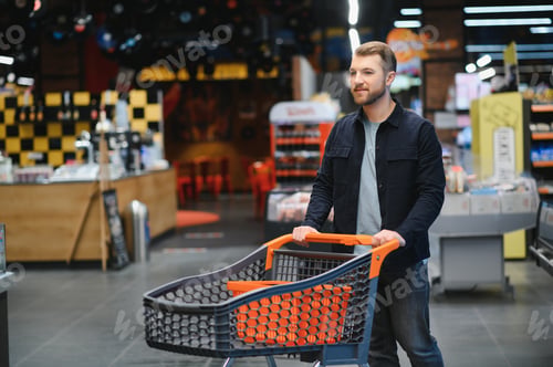 Preview: Portrait of smiling man walking with his trolley on aisle at supermarket.