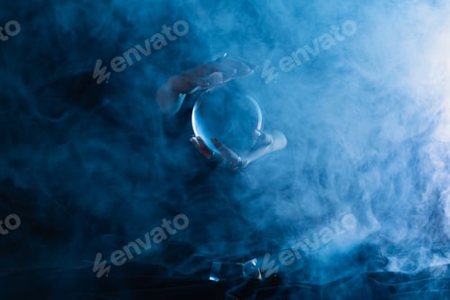 Preview: Cropped view of witch holding crystal ball on dark blue background