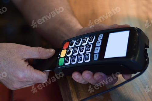 Preview: Man’s hand is holding payment machine to make credit or debit payment using chip card
