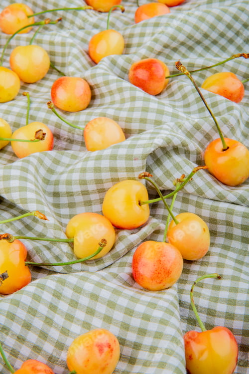 Preview: side view of yellow cherries on plaid cloth background