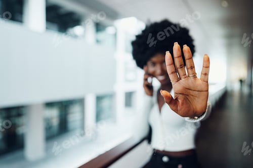 Preview: Portrait of a serious young african woman showing stop gesture with her palm in urban background