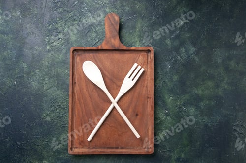 Preview: top view plastic utencils fork and spoon inside wooden cutting board on dark background knife