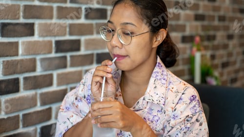 Preview: Asia holding A Glass of water and Drinking in the shop on wall back ground