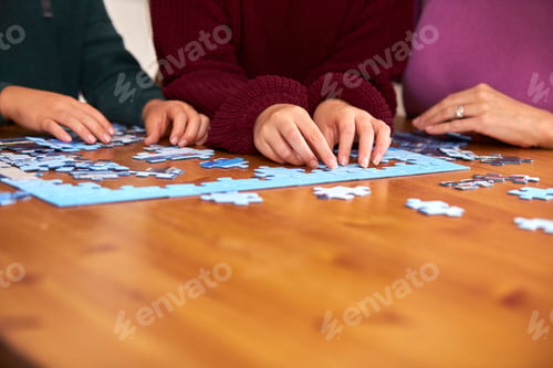 Preview: Close Up Of Family Sitting Around Table At Home Doing Jigsaw Puzzle Together