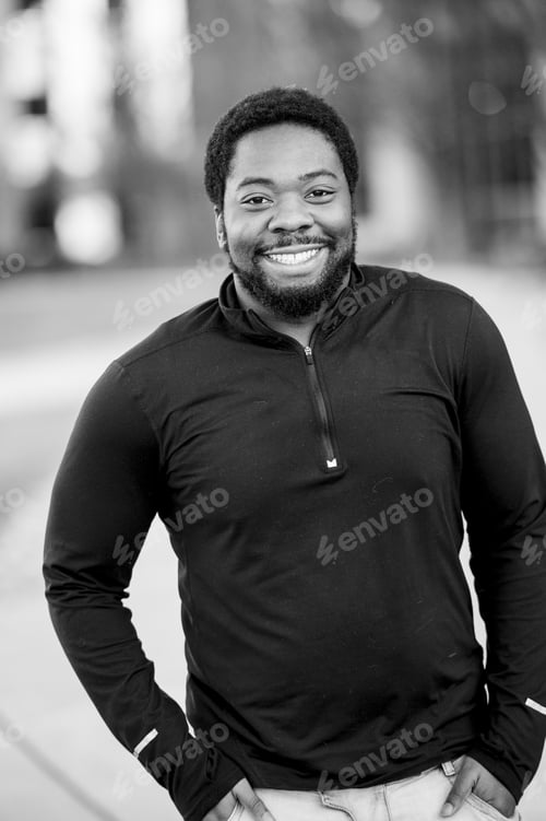 Preview: Vertical greyscale shot of an attractive African American male smiling at the camera