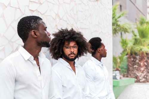 Preview: an elegant afro man looking at the camera while standing together with his colleagues outdoors