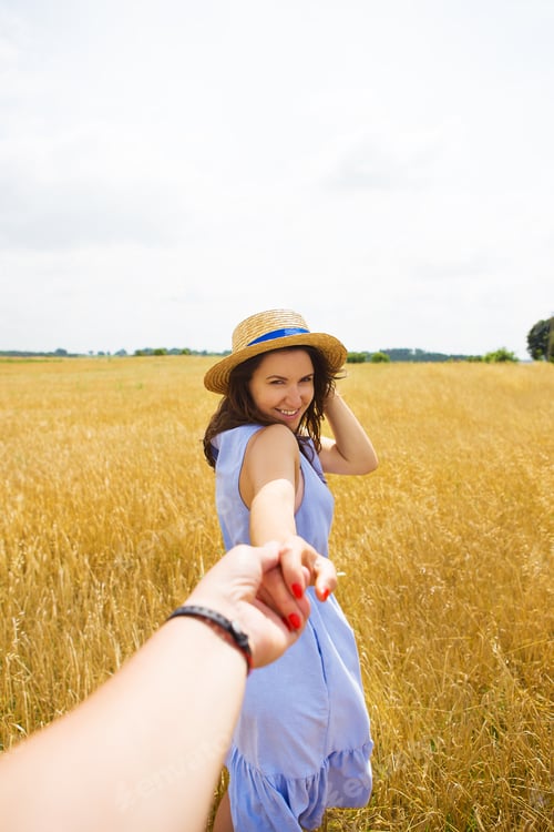 Preview: a girl in a blue dress is standing with her back in a wheat field