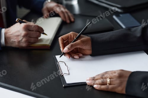 Preview: Black Woman Writing on Clipboard Working with Male Colleague at Business Meeting