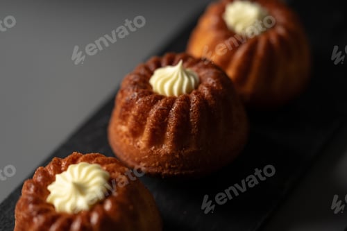 Preview: Delicious mini bundt cakes displayed on a dark platter with creamy frosting on top
