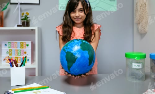 Preview: Female student holding a handmade globe world at ecology classroom