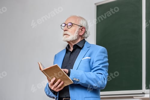 Preview: senior lecturer holding book and looking away