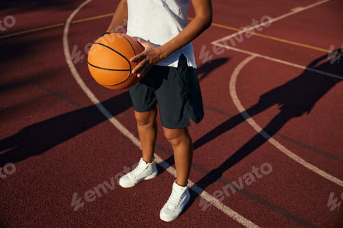 Preview: Closeup view on basketball ball in hand of young girl player