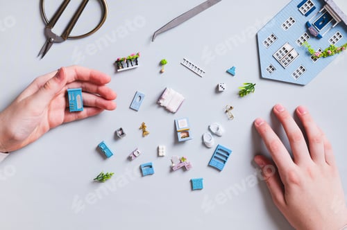 Preview: Miniature details and furniture for a toy house and children's hands on a blue top view