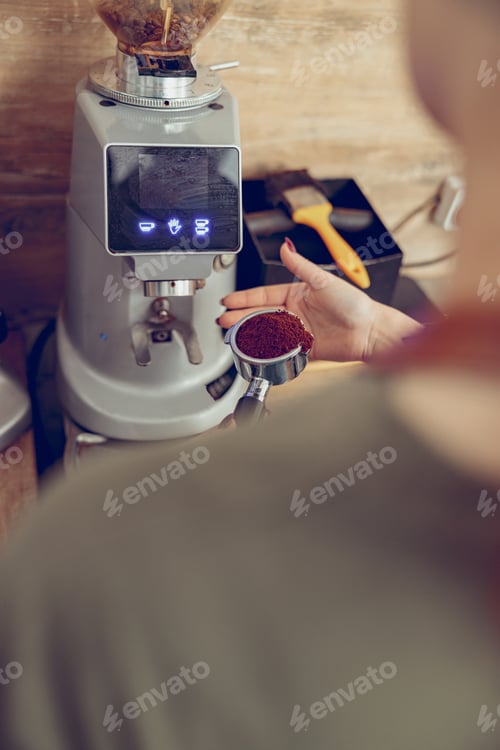 Preview: Young woman using professional coffee machine in cafe