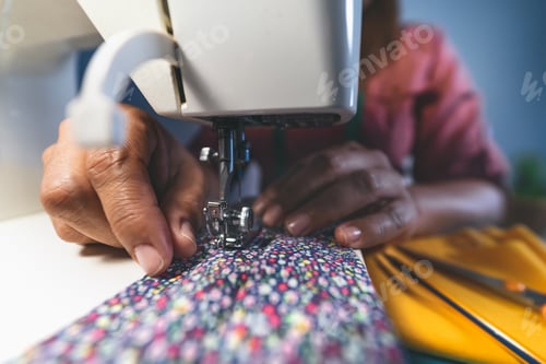 Preview: Mature woman working with sewing machine doing homemade medical face mask