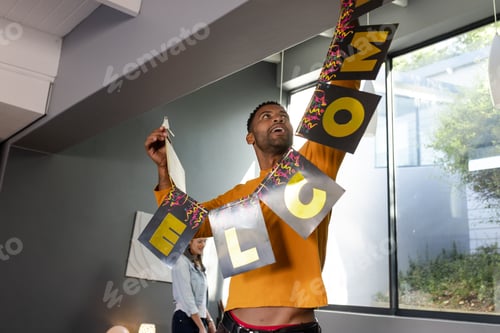 Preview: Man hanging welcome banner in modern living room, preparing for celebration