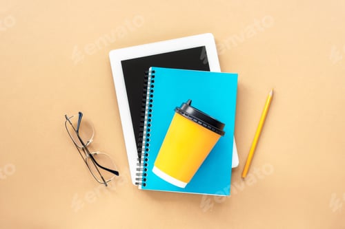 Preview: Tablet computer, blue notepad, glasses and yellow coffee cup on the table. Study concept. Top view