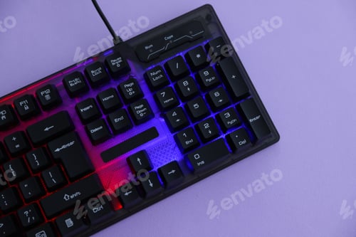 Preview: Modern computer keyboard with RGB lighting on violet background, top view. Space for text