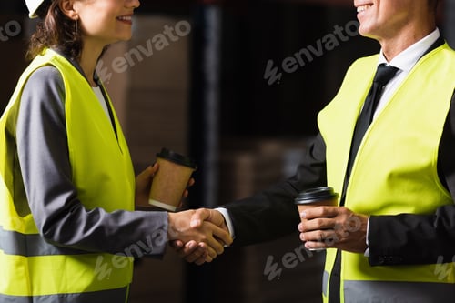 Preview: cropped view of happy supervisor and his colleague holding paper cups with coffee and shaking hands