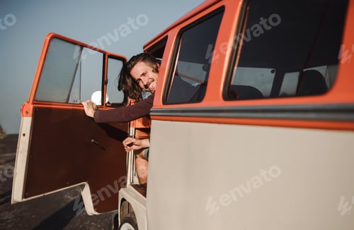 Preview: A young man getting out of a car on a roadtrip through countryside. Copy space.