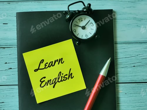 Preview: Phrase learn English written on sticky note with a pen,alarm clock and book.