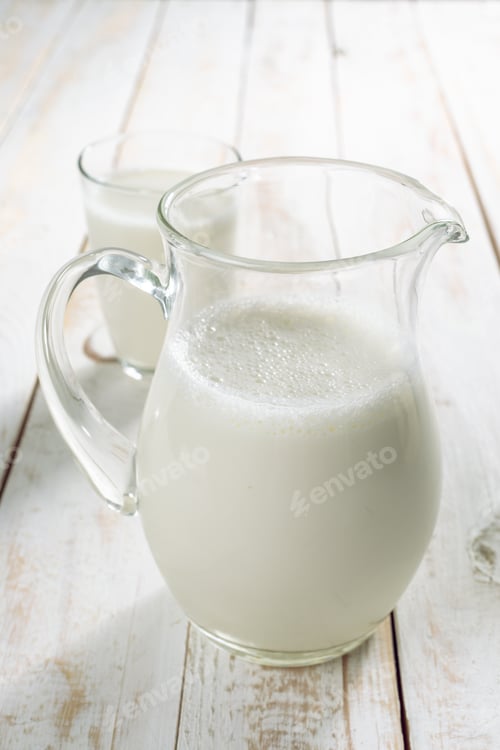 Preview: fresh milk in glass jug and glass on wooden background