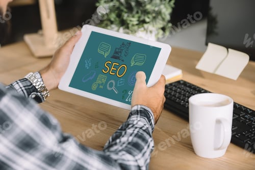 Preview: cropped shot of developer using tablet with SEO icons at workplace