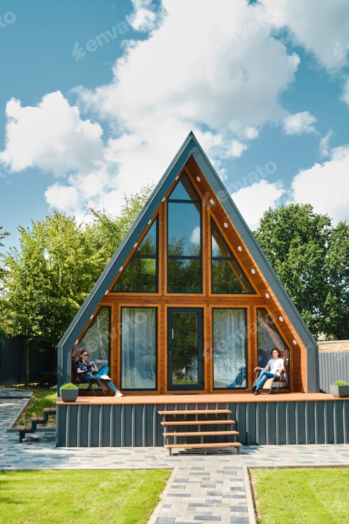 Preview: Mother and daughter sitting on a folding chairs on the terrace of a tiny house