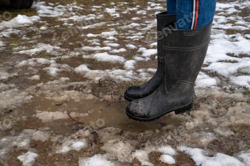 Preview: person about to jump into a muddy puddle with black gumboots on