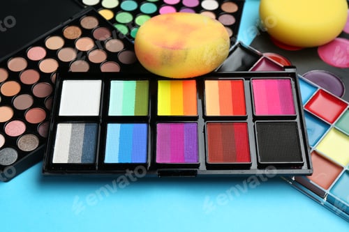 Preview: Bright face paints and sponges on light blue background, closeup