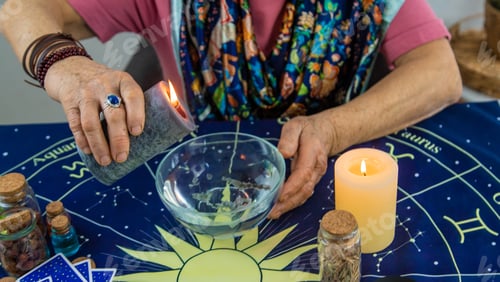 Preview: Woman fortune teller fortune telling wax candles. Selective focus.