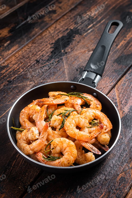 Preview: Fried with butter and garlic prawns shrimps in a skillet. Wooden background. Top view
