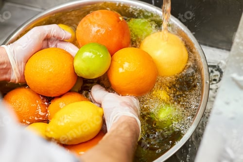 Preview: Chef washing mix of citrus fruits in a sink.