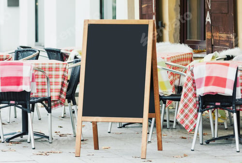 Preview: Blank restaurant menu chalkboard, cafe blackboard mockup on the street with empty cafe seats