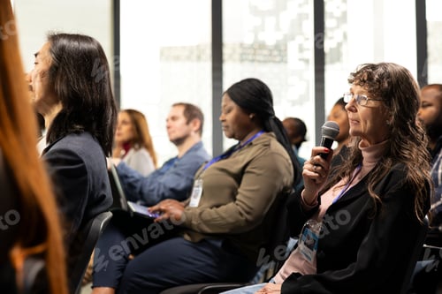 Preview: Senior woman in audience using microphone to ask multiple questions