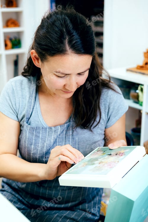 Preview: Woman Artist craftsman works in creative workshop and decorates box using decoupage technique