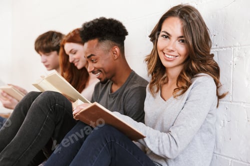 Preview: Friends students sitting over white wall. Focus on cheerful woman.