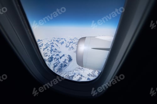 Preview: View from airplane window during flight above snowcapped mountains of Greenland.