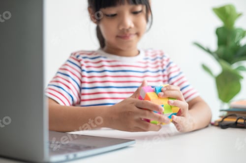 Preview: Asian little cute girl holding Rubik's cube in her hands. Rubik's cube is a game that increases the